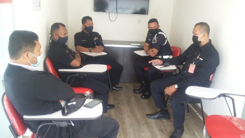 SAGAS director Tulus and security guards in focused discussion inside a container‑based command center setup