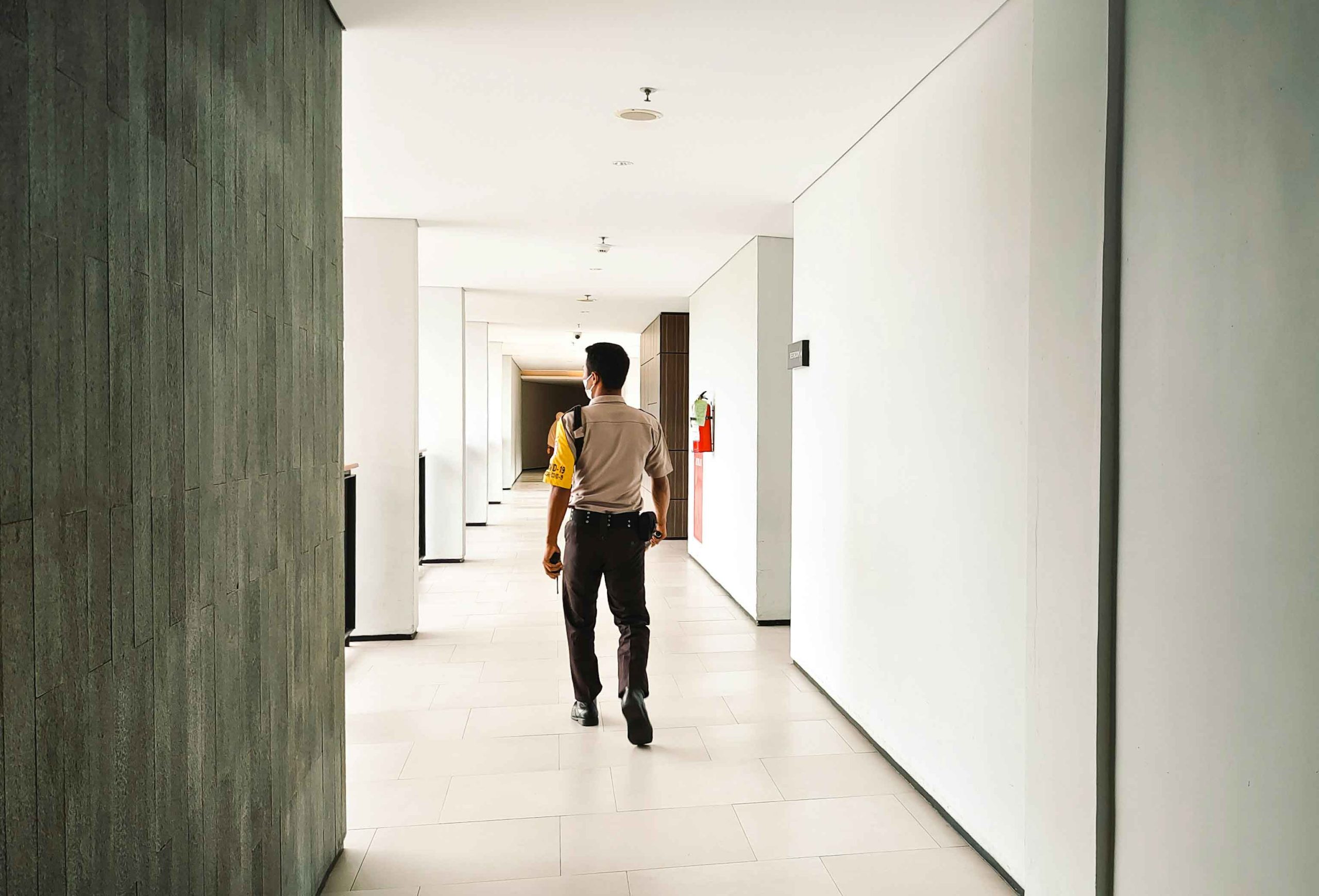 Security guard walking along an indoor corridor in a hotel or residential building