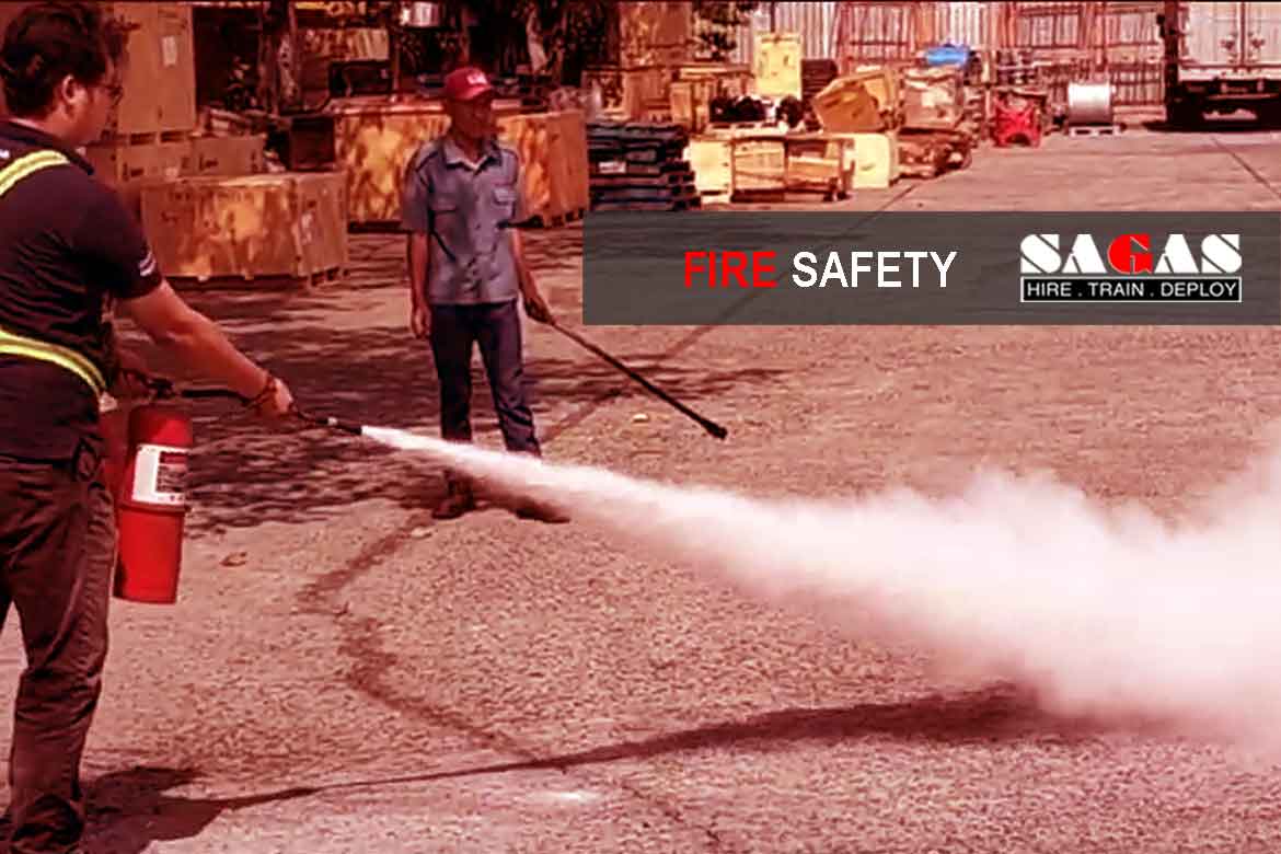 Warehouse staff at a SAGAS client site participating in workplace fire safety training, practicing fire extinguisher use to enhance emergency preparedness and team safety awareness